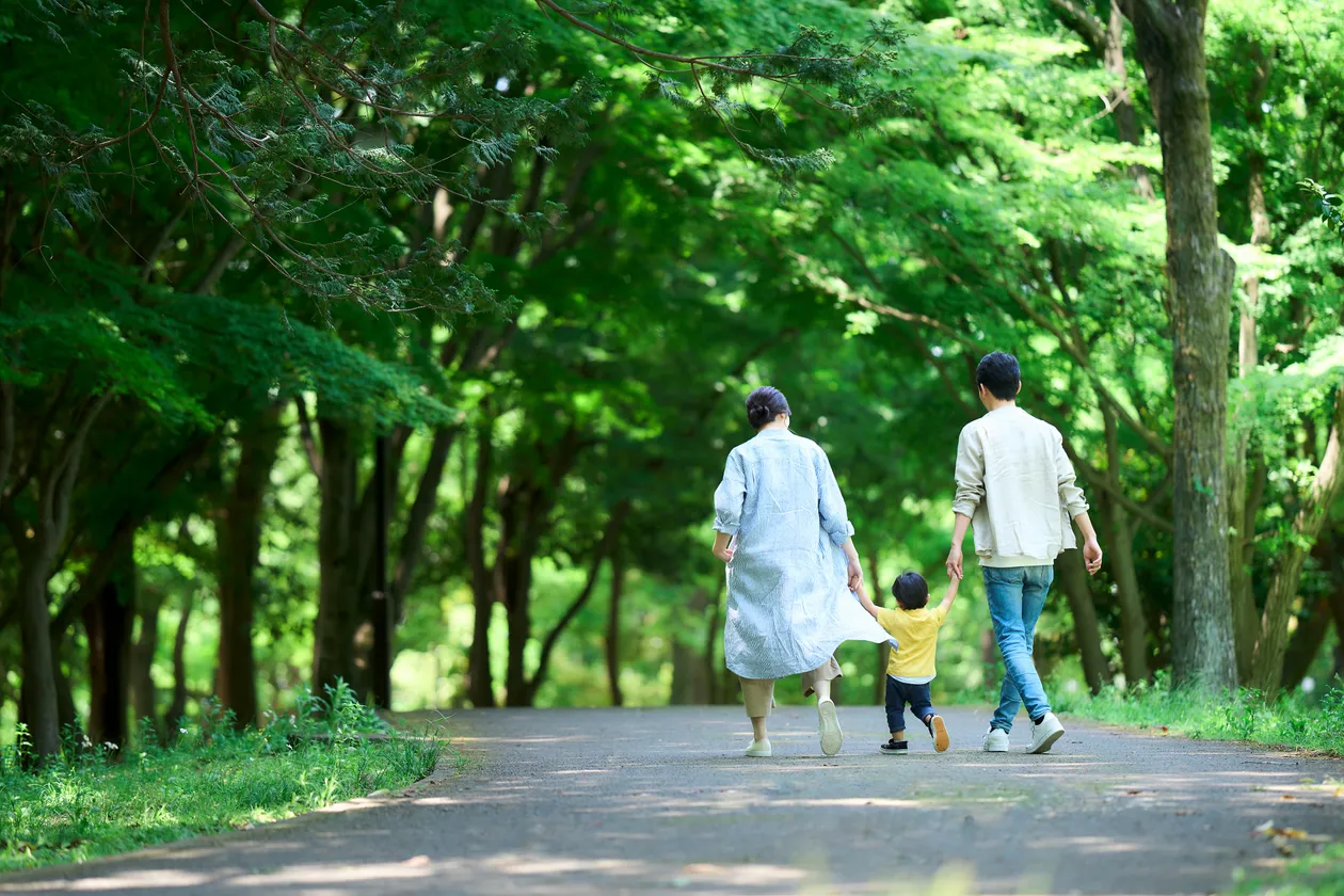 手を繋いで歩く家族の画像